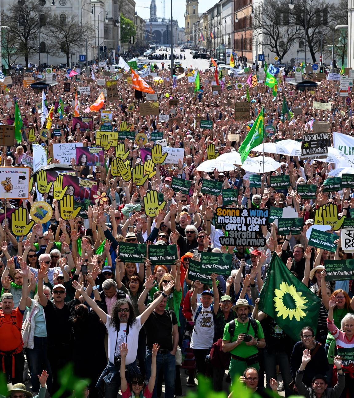 18.04.2026, Bayern, München: Demonstranten heben bei der Demonstration unter dem Motto Erneuerbare Energien verteidigen ihre Hände vor dem Siegestor.