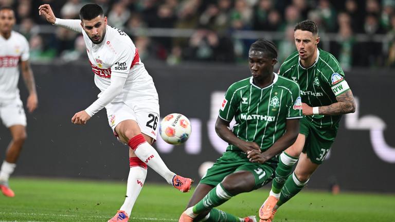 Stuttgarts Stürmer Deniz Undav schießt den Ball in Richtung des Bremer Tors, wird dabei jedoch von Bremens Karim Coulibaly und Marco Friedl bedrängt.