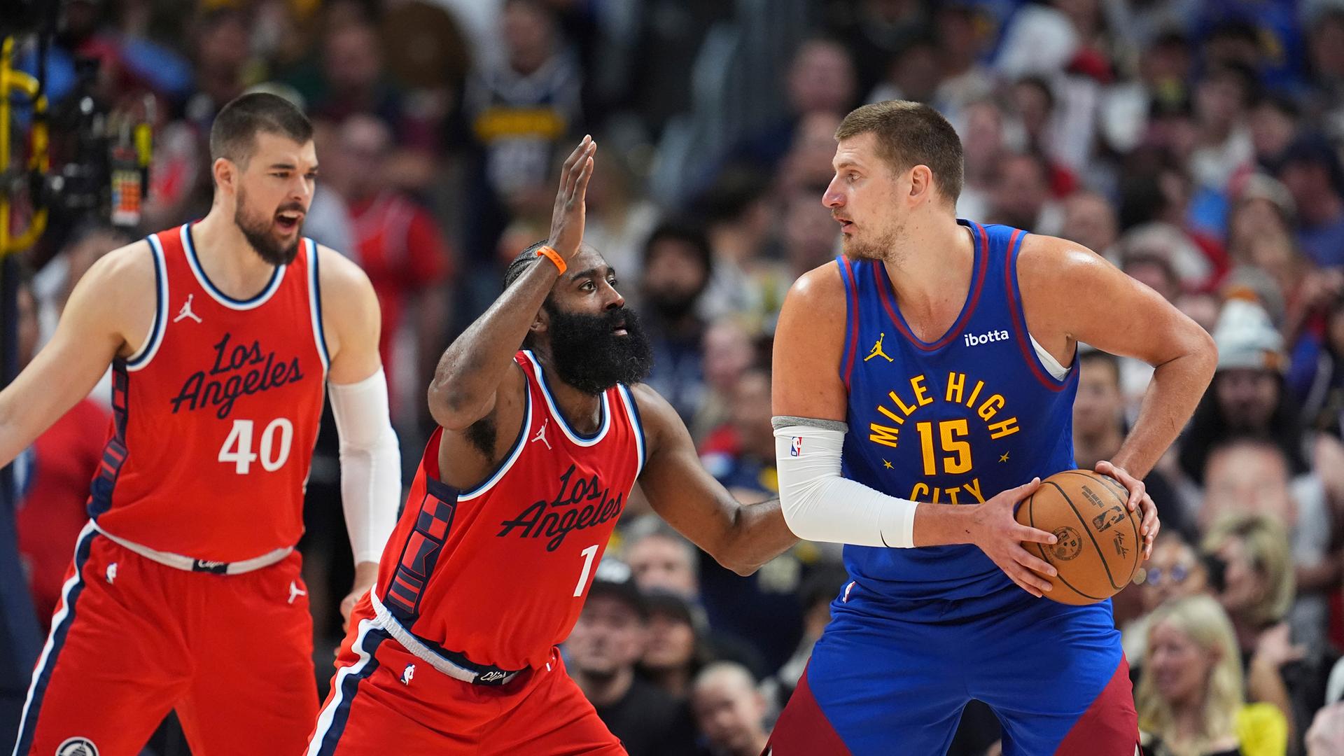 USA, Denver: Basketball: NBA, Denver Nuggets - Los Angeles Clippers; Play-off-Runde, Western Conference, Viertelfinale, 7. Spieltag: Denver Nuggets-Center Nikola Jokic, rechts, versucht, den Ball zu passen, während Los Angeles Clippers-Guard James Harden, Mitte, und Center Ivica Zubac, links, verteidigen.