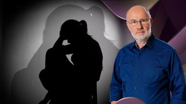 Harald Lesch steht neben trauriger Frau auf Stuhl