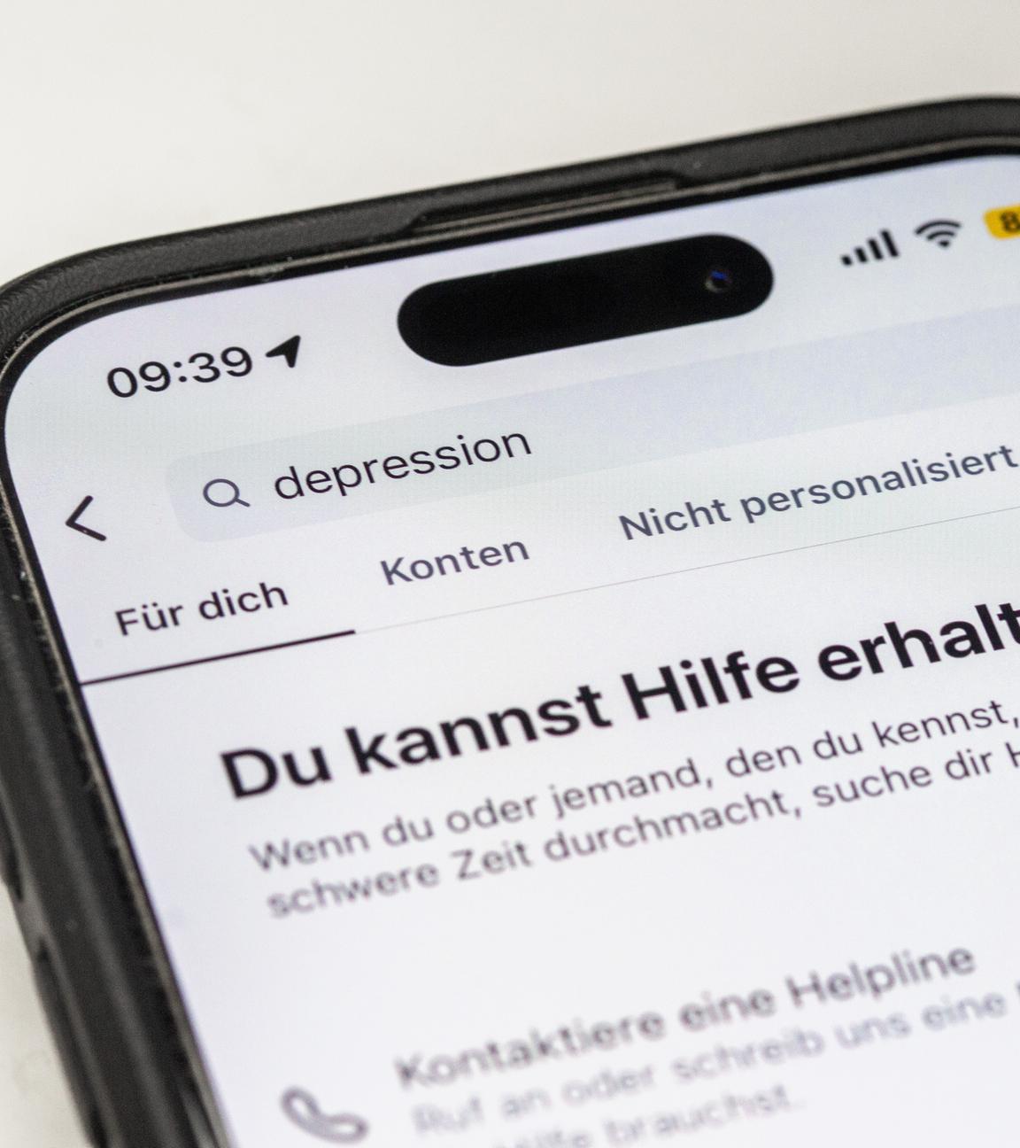 Auf einem Smartphone ist eine Suchansicht innerhalb einer Social-Media-App zu sehen, die bei dem Begriff «Depression» Hinweise auf Hilfsangebote und Unterstützung einblendet.