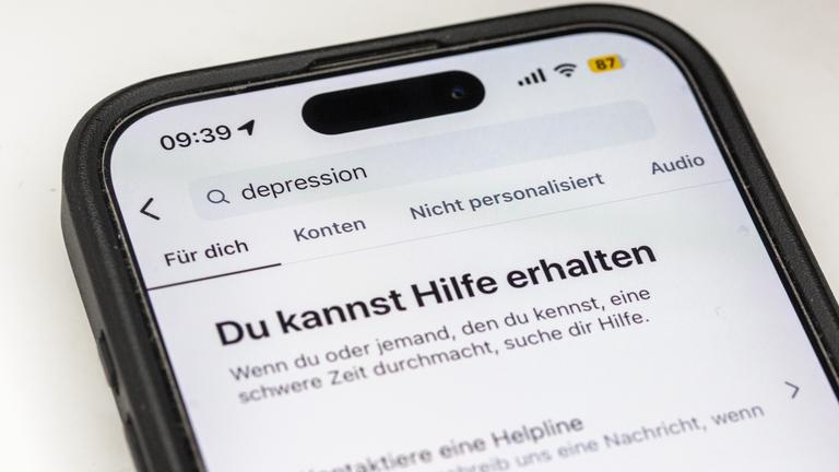 Auf einem Smartphone ist eine Suchansicht innerhalb einer Social-Media-App zu sehen, die bei dem Begriff «Depression» Hinweise auf Hilfsangebote und Unterstützung einblendet.