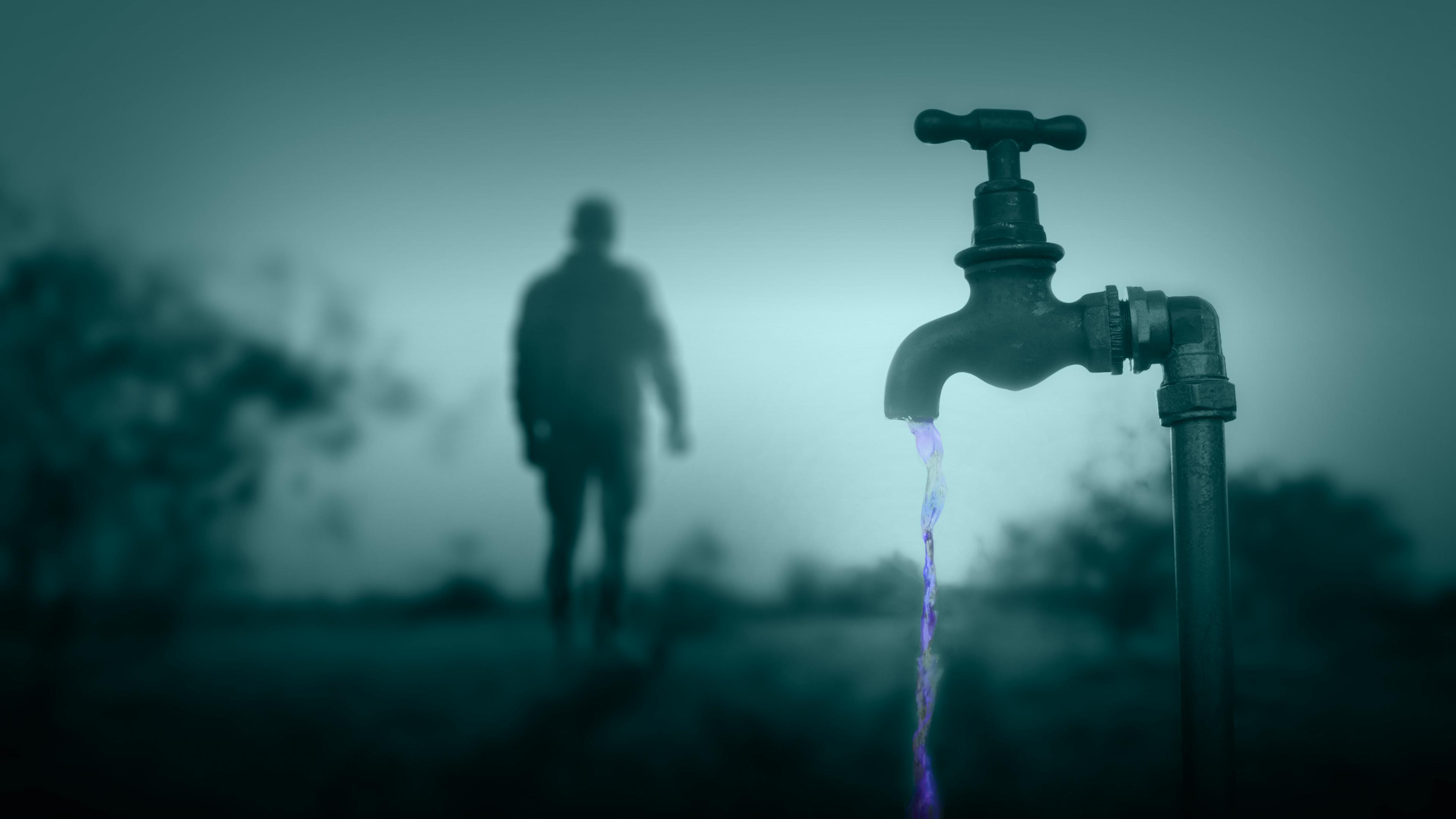 Im Vordergrund ein Wasserhahn im schummrigen Dämmerlicht; im Hintergrund die Silhouette eines Mannes.