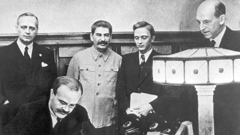 Am 23. august 1939 unterzeichneten der Außenminister des Deutschen Reiches, Joachim von Ribbentrop (l), und der sowjetische Außenminister Wjatscheslaw Molotow (vorn) in Moskau den deutsch-russischen Nichtangriffspakt. Hinten neben Ribbentrop Josef Stalin, ganz rechts Friedrich Gaus, daneben U. Pavlov.