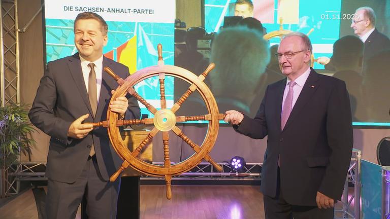 Sven Schulze und Rainer Haselhoff halten ein Sterurad aus Holz fest