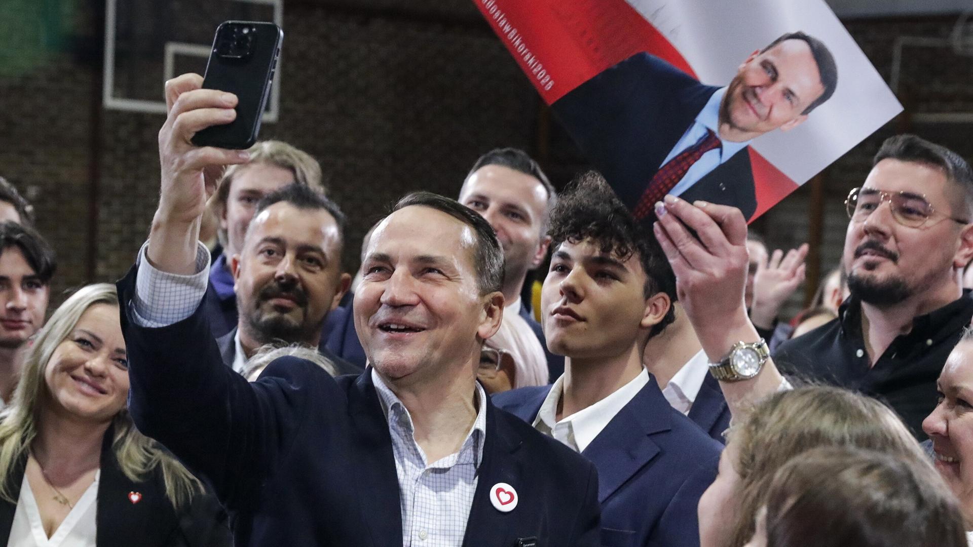 Der polnische Außenminister Radoslaw Sikorski (Mitte) von der Regierungspartei Bürgerplattform posiert für ein Selfie während seines Treffens mit Anwohnern in Pruszkow, Zentralpolen, 17. 11. 2024.