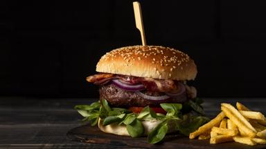 Ein Hamburger und eine Portion Pommes frites auf einem Tisch.
