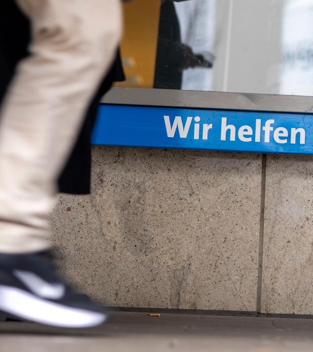 Menschen gehen an der Außenstelle Mainz (Stadt) vorbei, lokaler Ansprechpartner in Sachen Kriminalprävention und Opferhilfe des Weißen Ring e.V. in Mainz, gemeinnütziger Verein zur Unterstützung von Kriminalitätsopfern und deren Familien sowie zur Verhütung von Straftaten. Auf dem Fenster steht: "Wir helfen Kriminalitätsopfern".