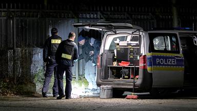 Einsatzkräfte der Polizei untersuchen den Ort einer Explosion außerhalb eines Zauns an einem Polizeigelände in Berlin-Wittenau.