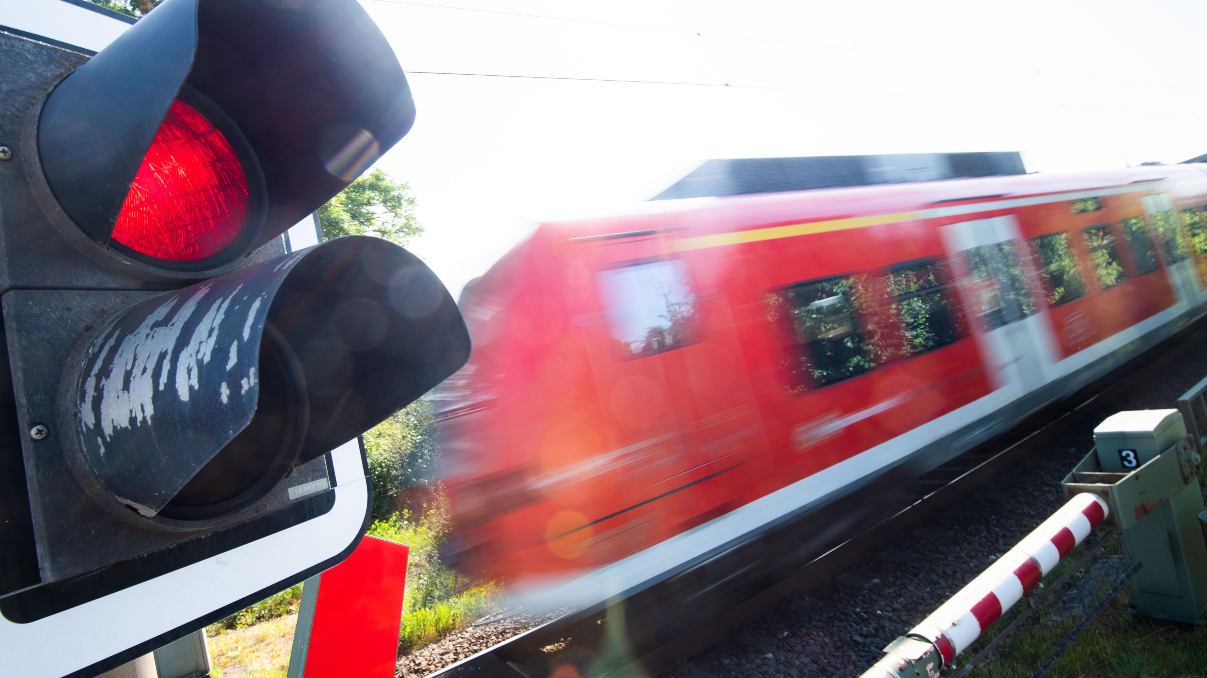 Eine S-Bahn der Deutschen Bahn (DB) fährt an einem Bahnübergang mit einer roten Ampel