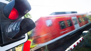 Eine S-Bahn der Deutschen Bahn (DB) fährt an einem Bahnübergang mit einer roten Ampel