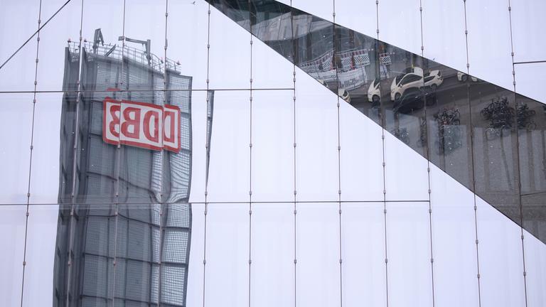 he logo of the Deutsche Bahn reflects in the glass surface of a building at Berlin Central Station in Berlin