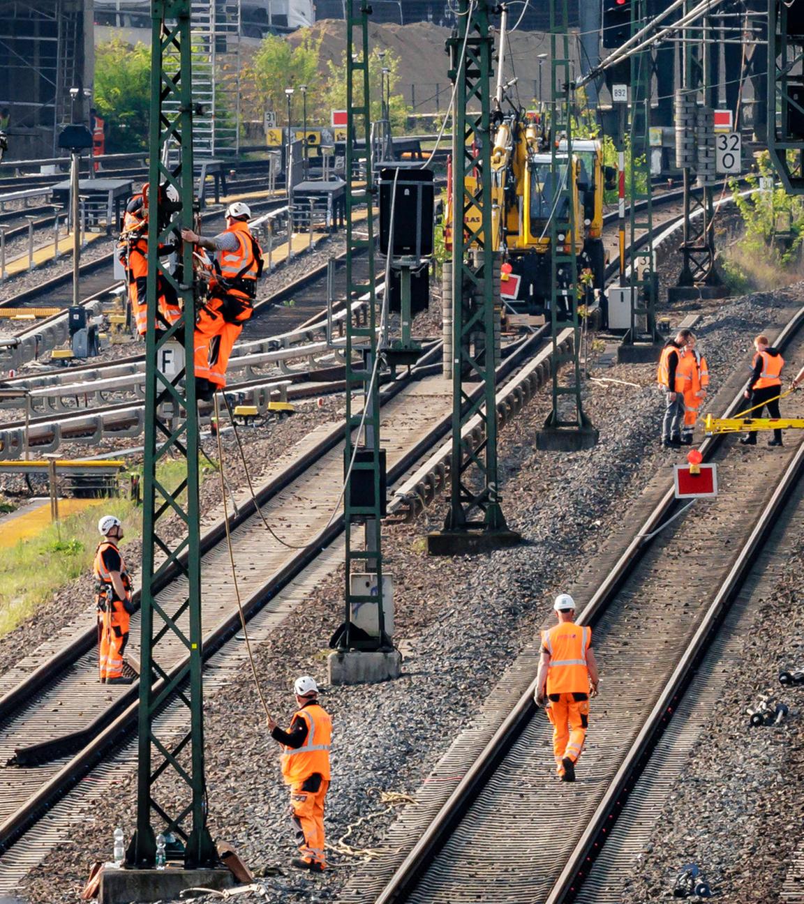 Tauben sitzen auf einem Signal während im Hintergrund Arbeiter an den Gleisen einer gesperrten Bahnstrecke arbeiten. Berlin, 23.04.2025. 