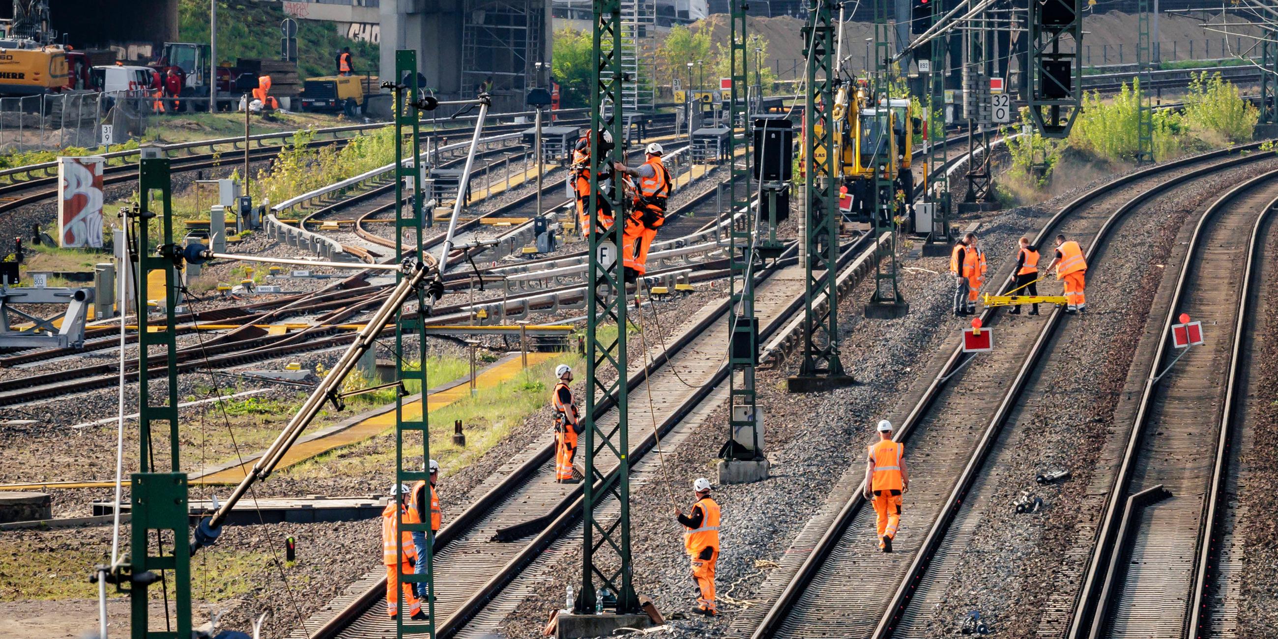 Tauben sitzen auf einem Signal während im Hintergrund Arbeiter der Bahn an den Gleisen einer gesperrten Strecke arbeiten. Berlin, 23.04.2025. 