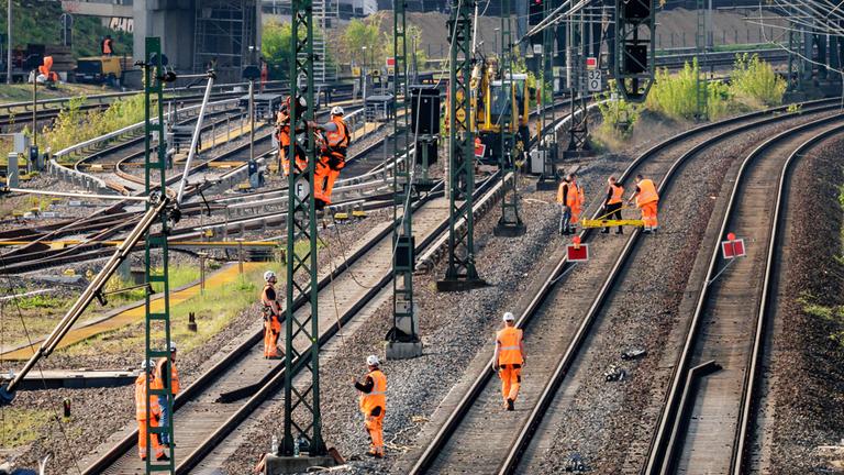 Tauben sitzen auf einem Signal während im Hintergrund Arbeiter an den Gleisen einer gesperrten Bahnstrecke arbeiten. Berlin, 23.04.2025. 
