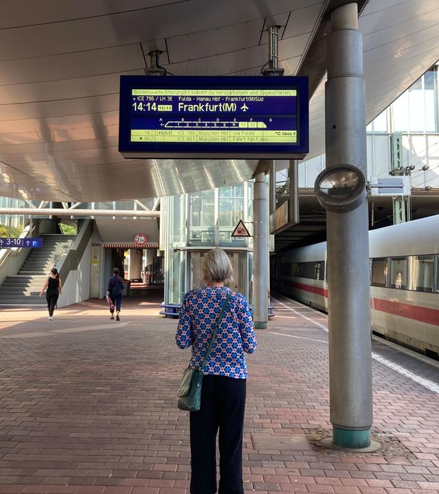 Kassel: Ein Frau steht auf dem Bahnsteig und schaut sich eine Anzeige der Deutsche Bahn an.