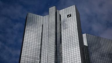 Wolken spiegeln sich auf der gläsernen Fassade der Zentrale der Deutschen Bank.