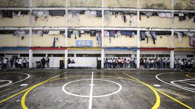 GInnenhof des Gefängnisses in Bogota, am Rand stehen mehrere Frauen. Aus den vergitterten Fenstern der Zellen hängt Wäsche.