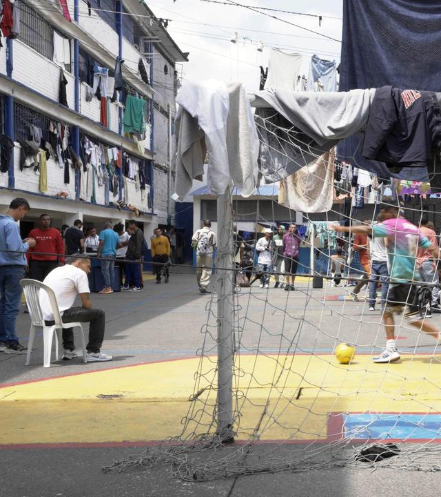 Gefängnishof von “La Modelo” in Bogota in Kolumbien: Auf dem Hof steht ein Tor, dahinter spielen Insassen Fußball. An den Seiten, an den Gebäuden hängt Wäsche zum Trocknen. 