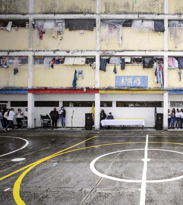 GInnenhof des Gefängnisses in Bogota, am Rand stehen mehrere Frauen. Aus den vergitterten Fenstern der Zellen hängt Wäsche.