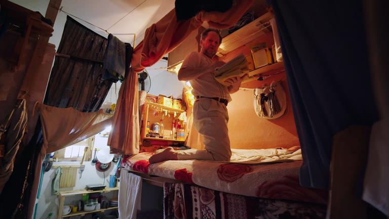 Der Deutsche Yves S. kniet im Gefängnis Juan Antonio de la Vega auf seinem Bett und hält Handtücher in den Händen. Über dem Bett befindet sich ein Regal.