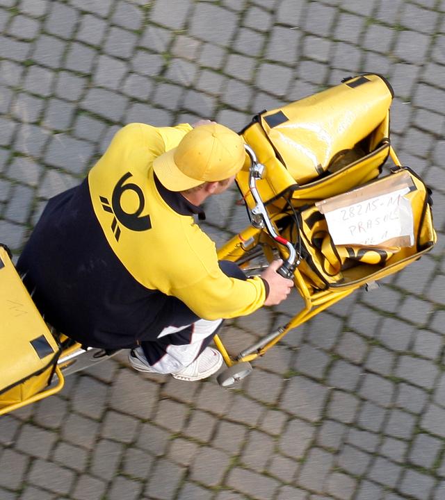 Ein Postbote fährt auf einem Postfahrrad.