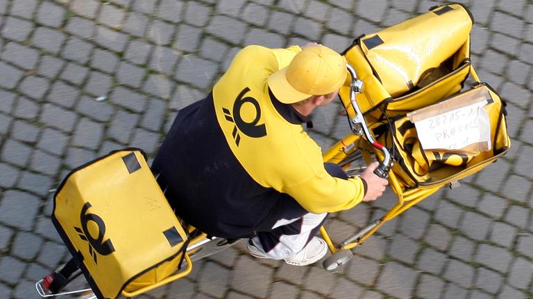 Ein Postbote fährt auf einem Postfahrrad.