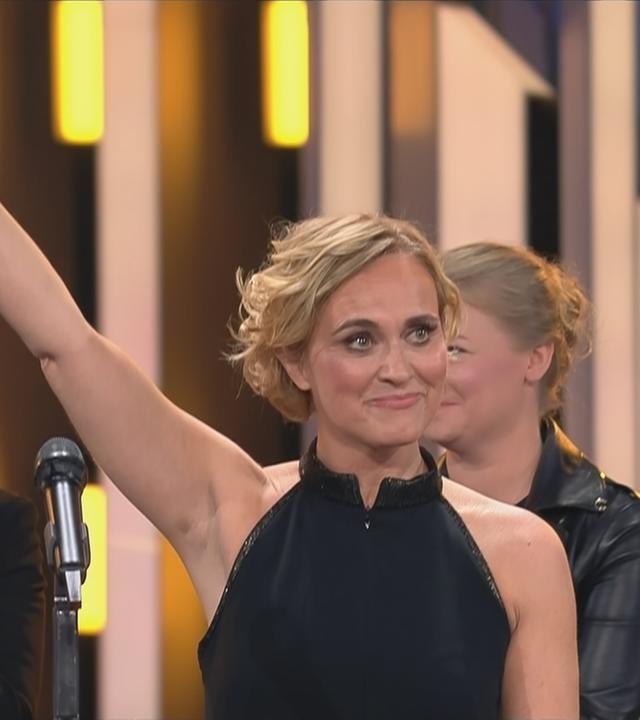 Auf dem Bild ist eine Frau zu sehen, die den deutschen Fernsehpreis in die Höhe hält.