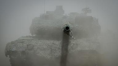 Ein Leopard 2 Kampfpanzer der Bundeswehr ist im Staub bei der Nato-Übung "Griffin Storm" zu sehen, das Kanonenrohr ragt aus der Staubwolke heraus.