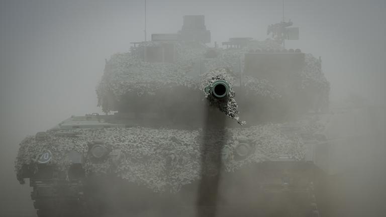 Ein Leopard 2 Kampfpanzer der Bundeswehr ist im Staub bei der Nato-Übung "Griffin Storm" zu sehen, das Kanonenrohr ragt aus der Staubwolke heraus.
