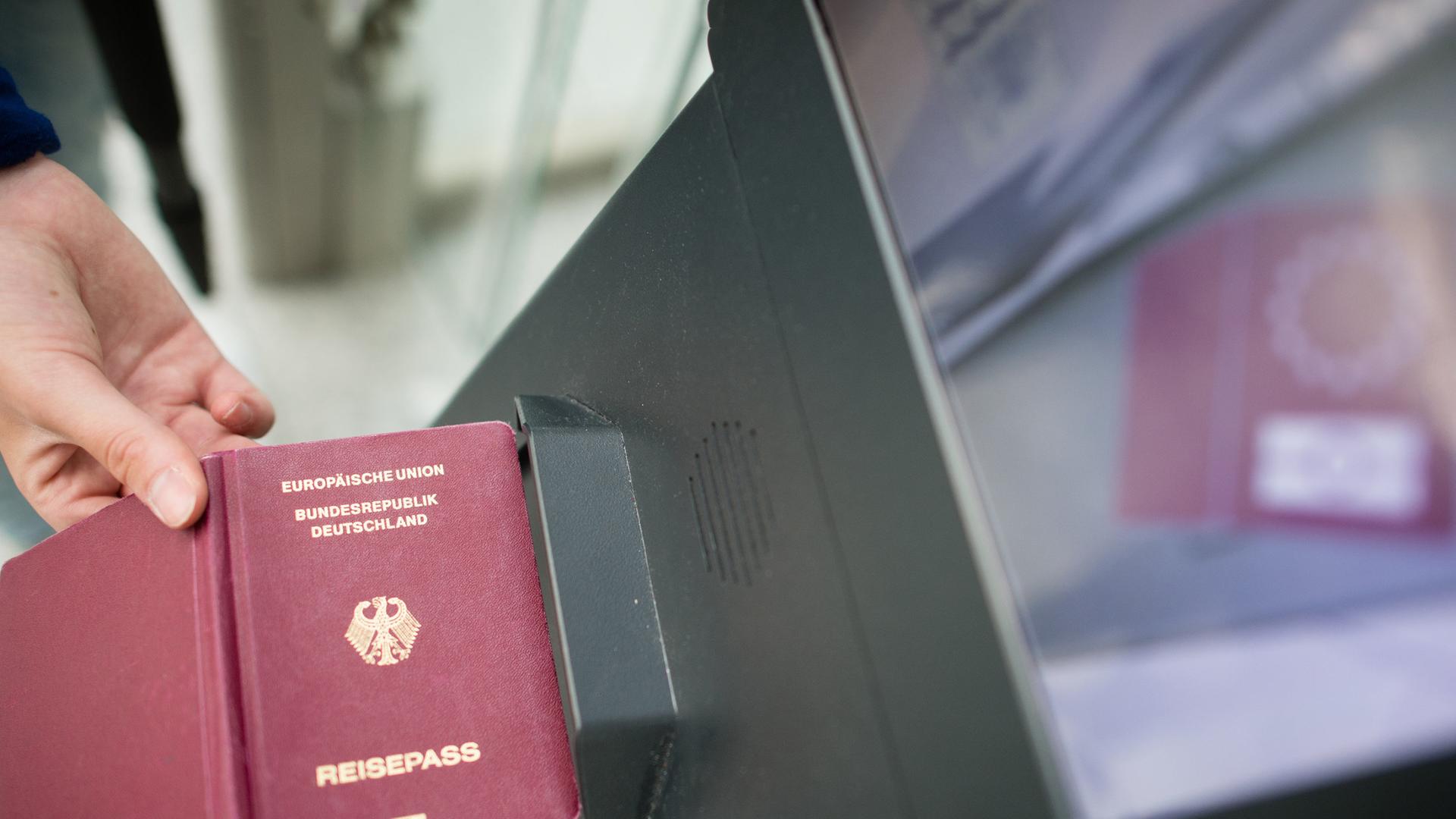 Eine Person am Flughafen hält ihren deutschen Reisepass an ein Gerät.