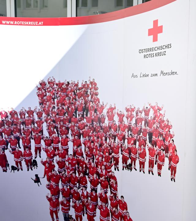 Eine Frau stellt ein Plakat des DRKs auf