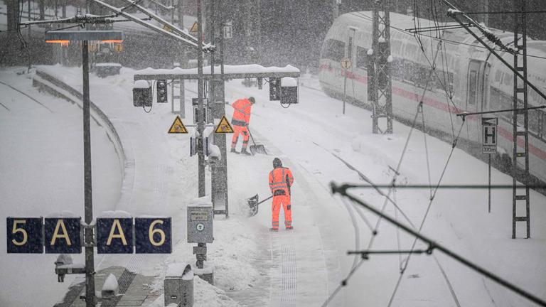 Hamburg: Arbeiter schaufeln am Hamburger Hauptnahnhof die schneebedeckten Gleise frei.