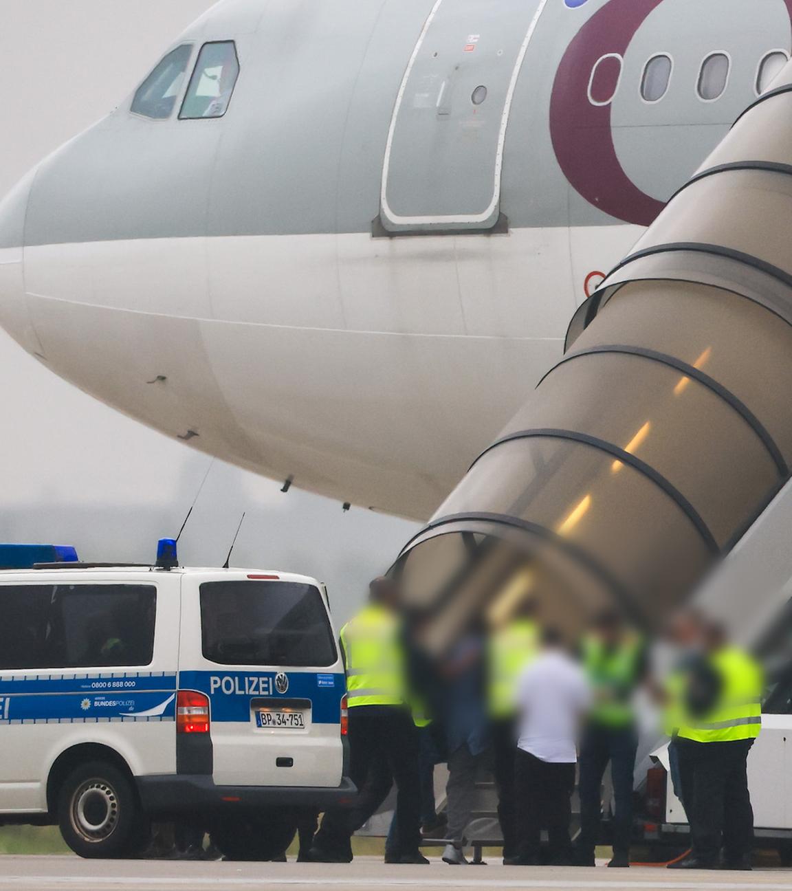 18.07.2025, Sachsen, Schkeuditz: Menschen besteigen ein Flugzeug der Qatar Airways, vor dem Fahrzeuge der Bundespolizei stehen auf dem Vorfeld am Flughafen Leipzig/Halle.
