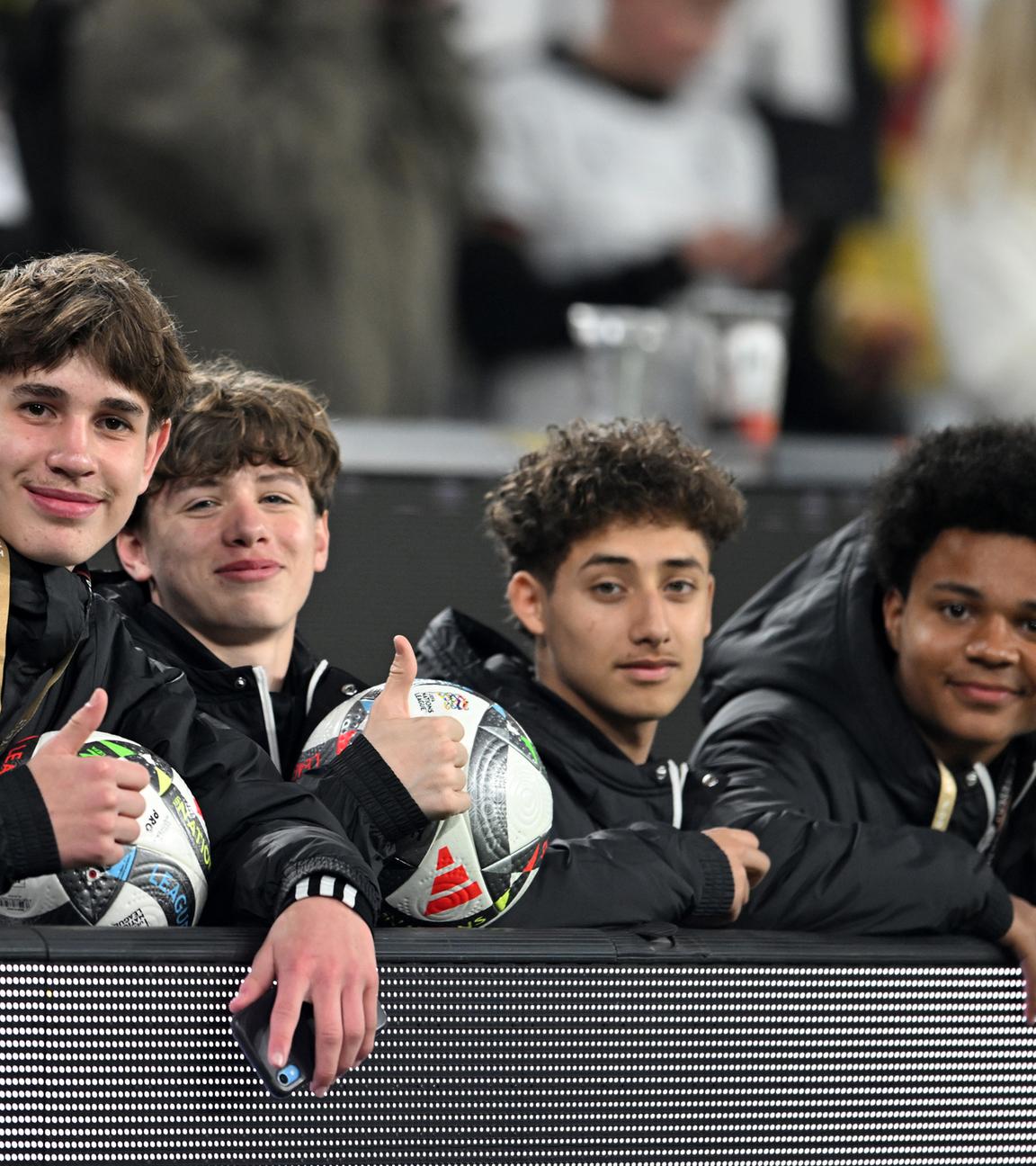 Balljunge Noel Urbaniak (l) und weitere Balljungen sitzen hinter der Bande.