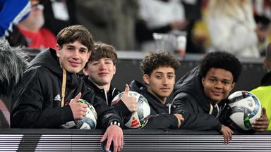 Balljunge Noel Urbaniak (l) und weitere Balljungen sitzen hinter der Bande.