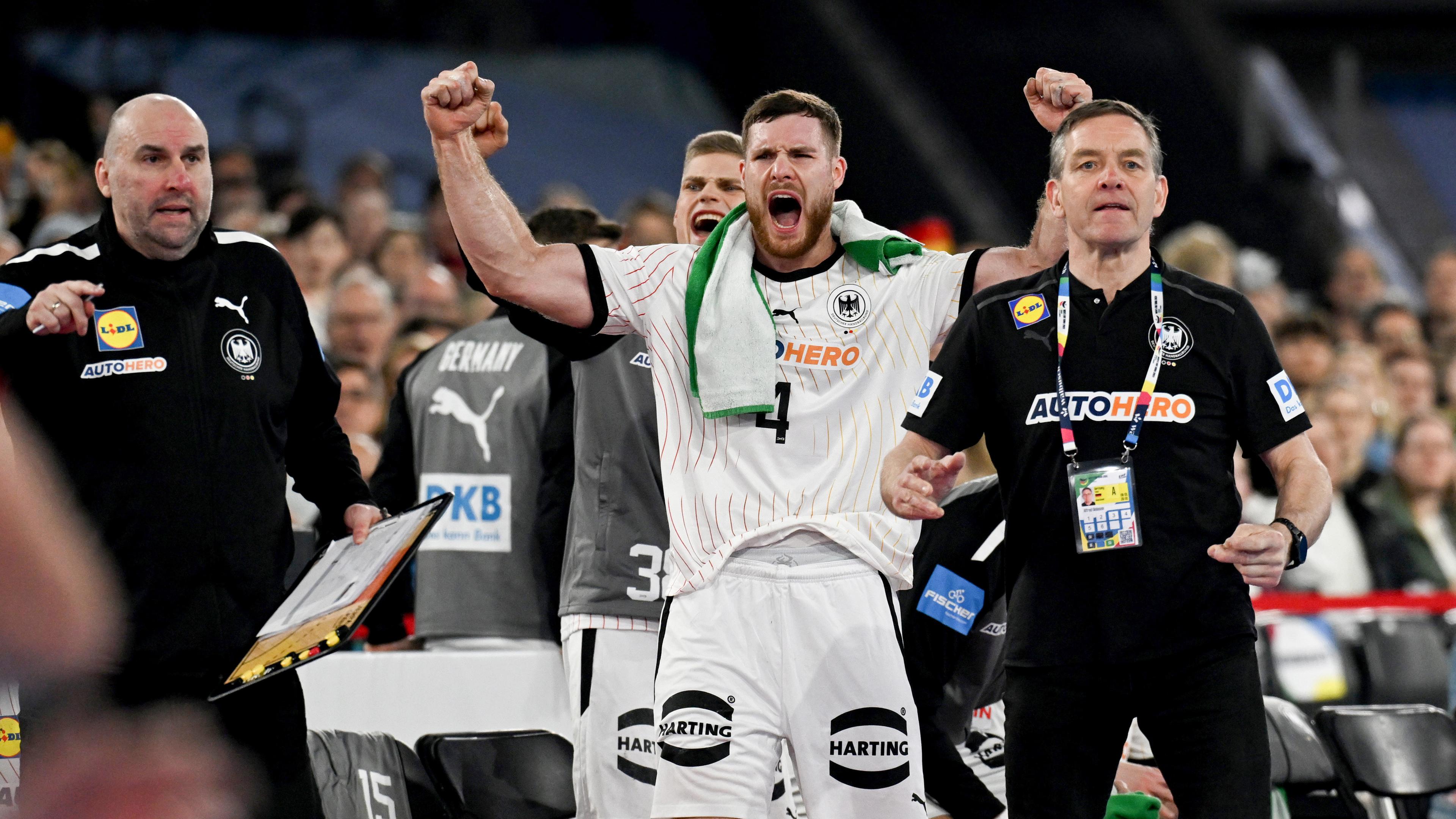 Deutschlands Johannes Golla (2.v.r.) jubelt während Bundestrainer Alfred Gislason (r) und Co-Trainer Erik Wudtke taktische Anweisungen geben.