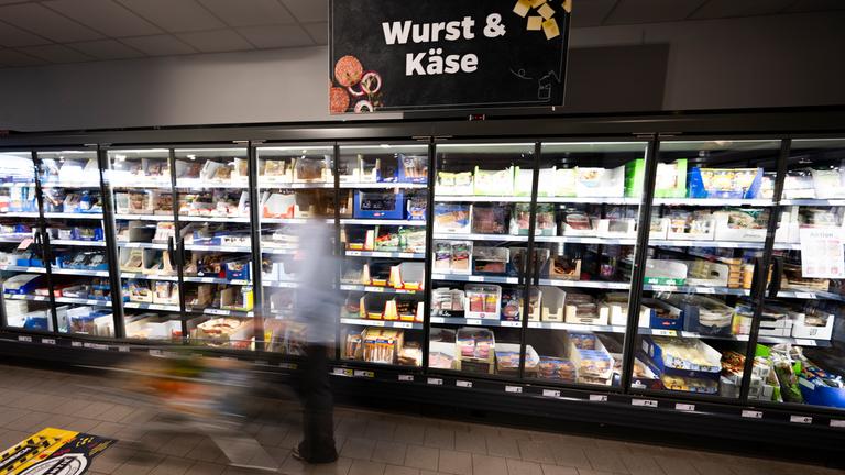 Eine Frau fährt mit ihrem Einkaufswagen vor dem Kühlregal eines Supermarkts. Mit dem "Deutschlandkorb" schlägt die SPD dem Lebensmittelhandel vor, Preise für bestimmte Grundnahrungsmittel freiwillig zu begrenzen. 