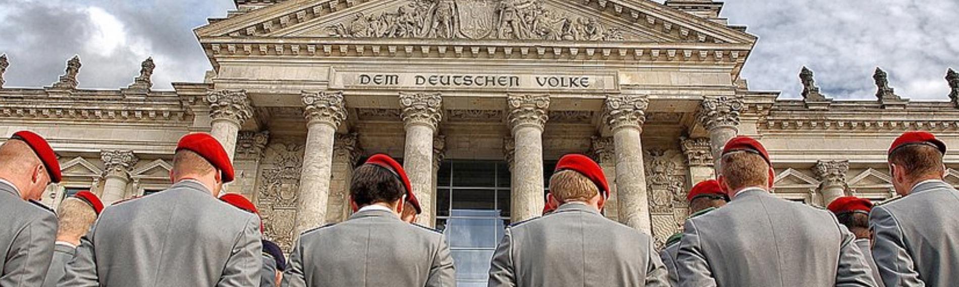Deutsche Soldaten stehen mit dem Rücken zur Kamera vor dem Reichstag.
