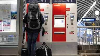 Eine Person kauft ein Bahnticket an einem Automaten