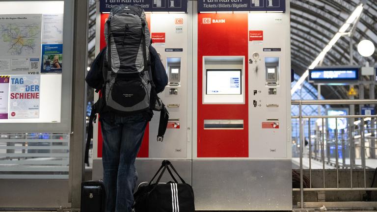 Eine Person kauft ein Bahnticket an einem Automaten