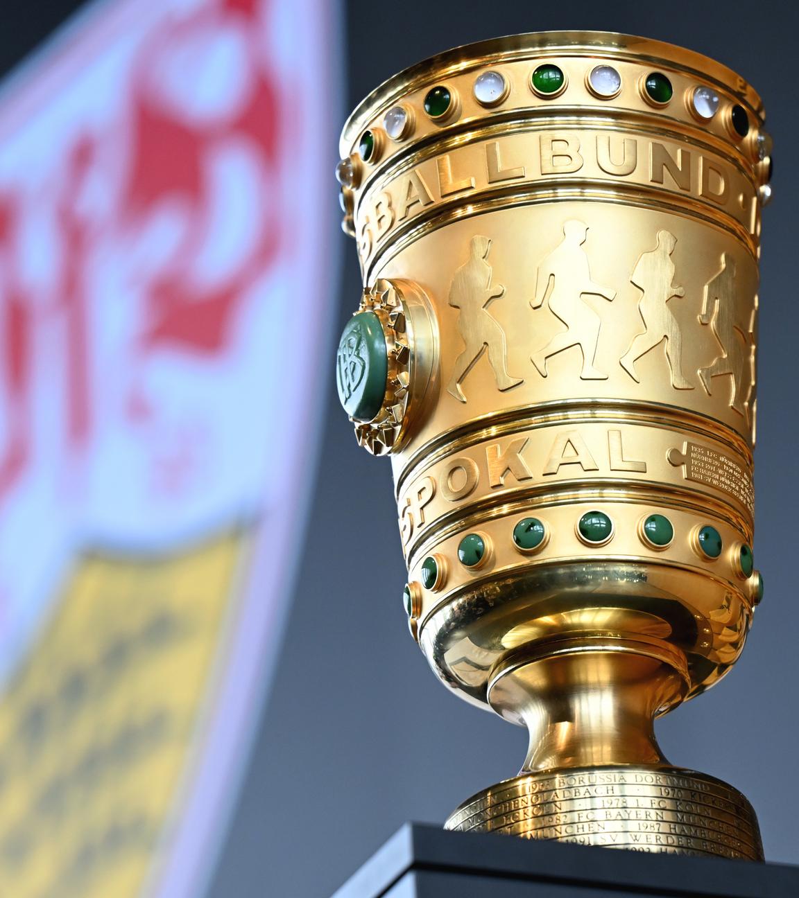 Der DFB-Pokal steht auf einem Tisch, im Hintergrund das Logo von Pokalverteidiger VfB Stuttgart.