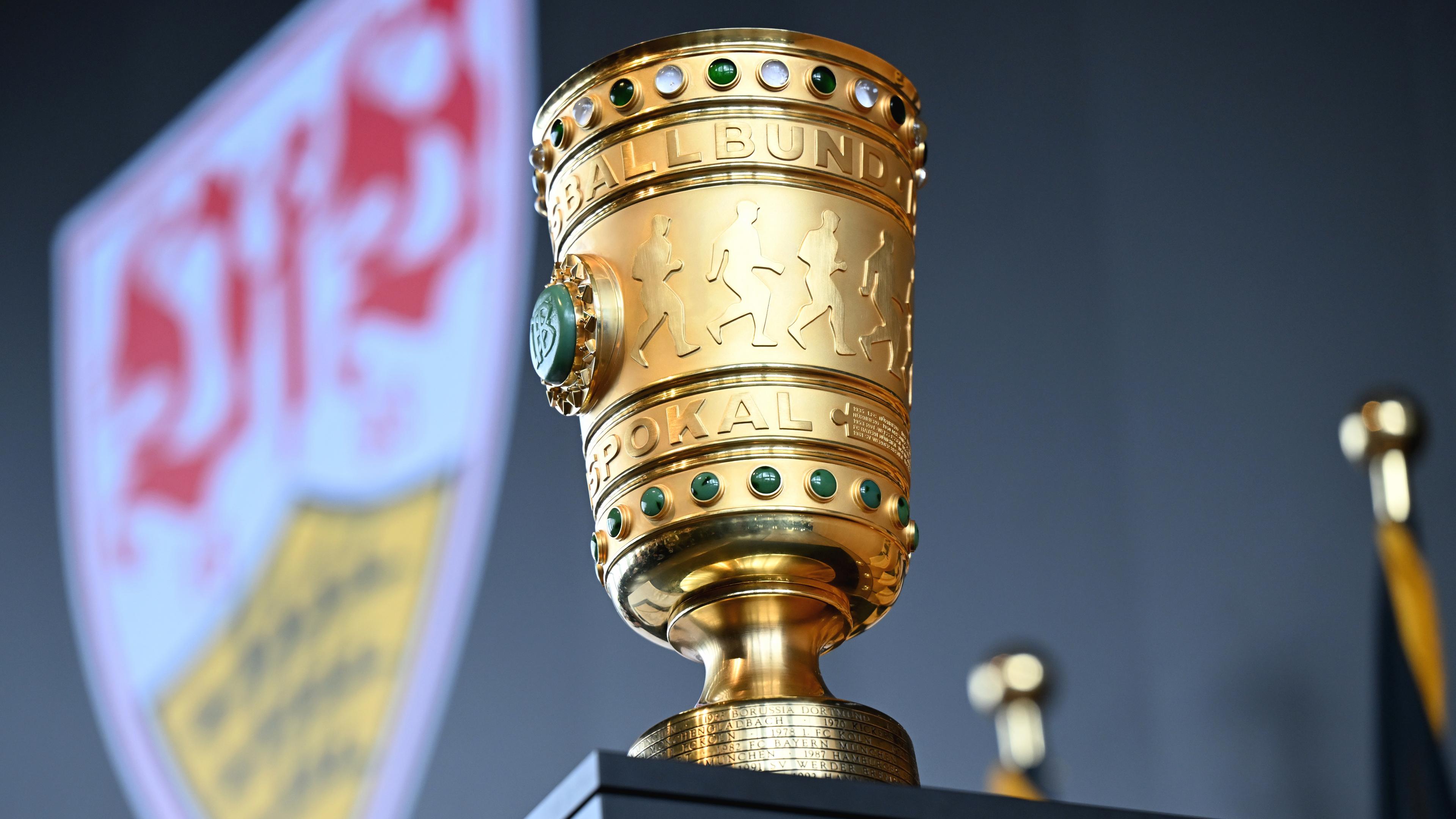 Der DFB-Pokal steht auf einem Tisch, im Hintergrund das Logo von Pokalverteidiger VfB Stuttgart.