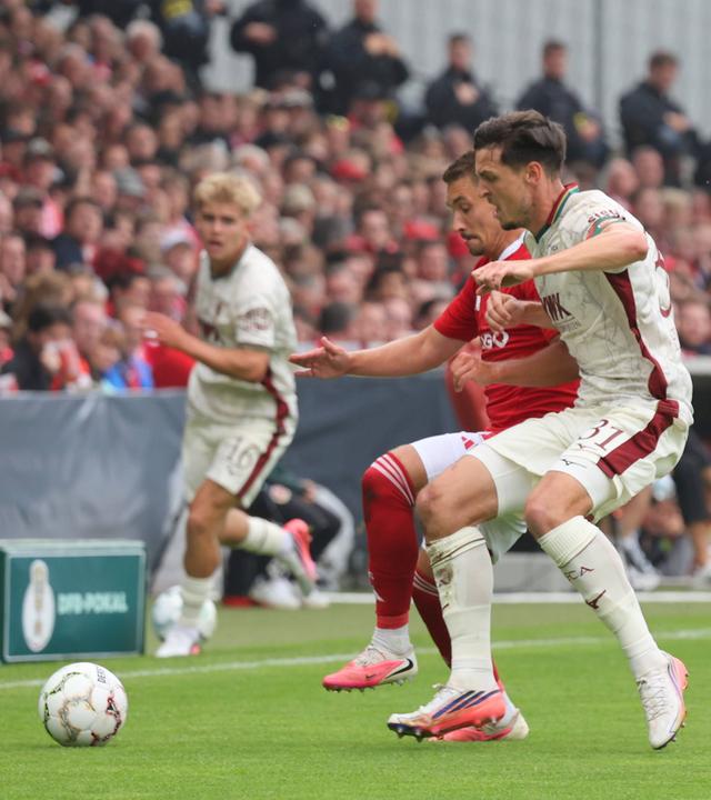 Julian Guttau (Energie Cottbus, l.) und Keven Matteo Schlotterbeck (FC Augsburg) im Zweikampf am 22.08.2026 in Cottbus.