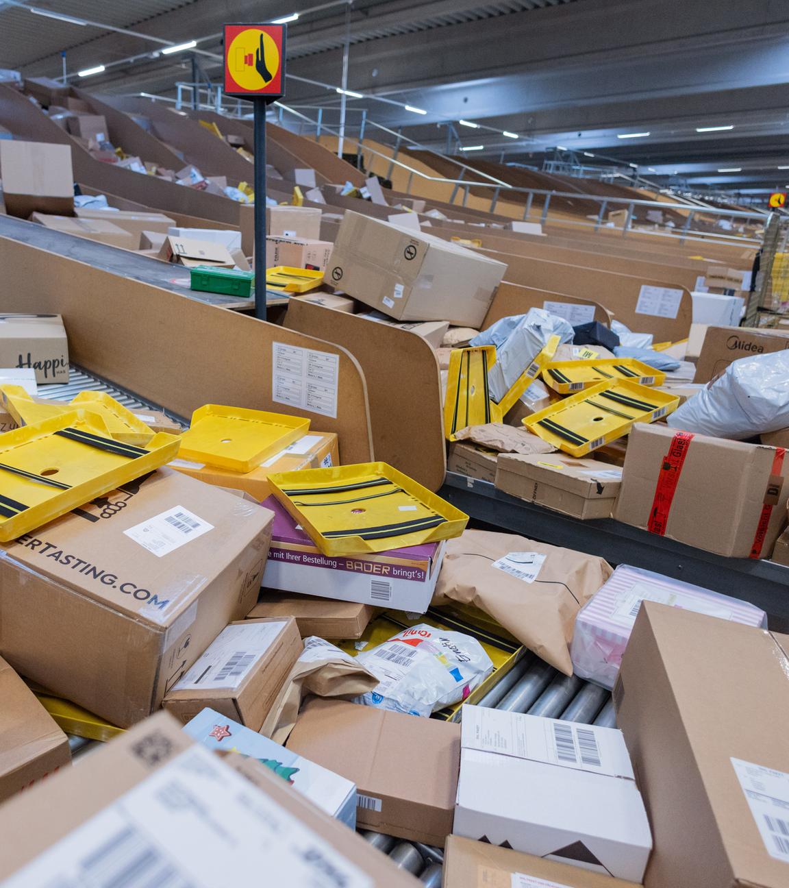 Ein Paketzusteller sortiert und räumt in einer Zustellbasis von Deutsche Post DHL Pakete in ein Zustellfahrzeug.