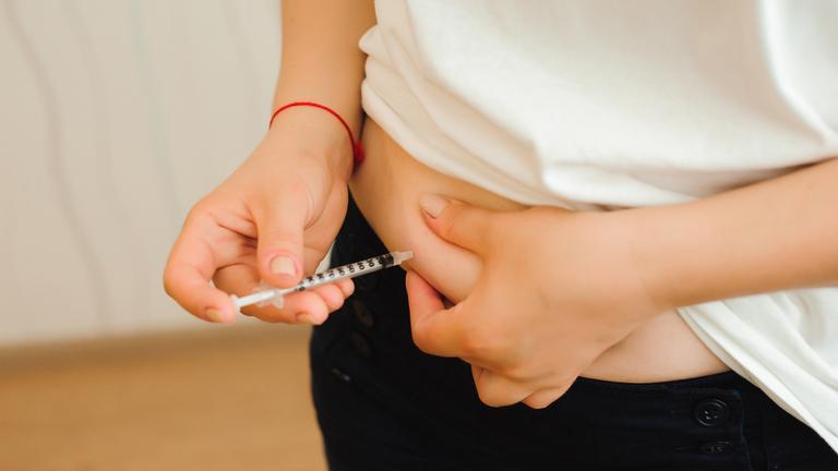 Patientin spritzt sich Insulin in den Bauch.