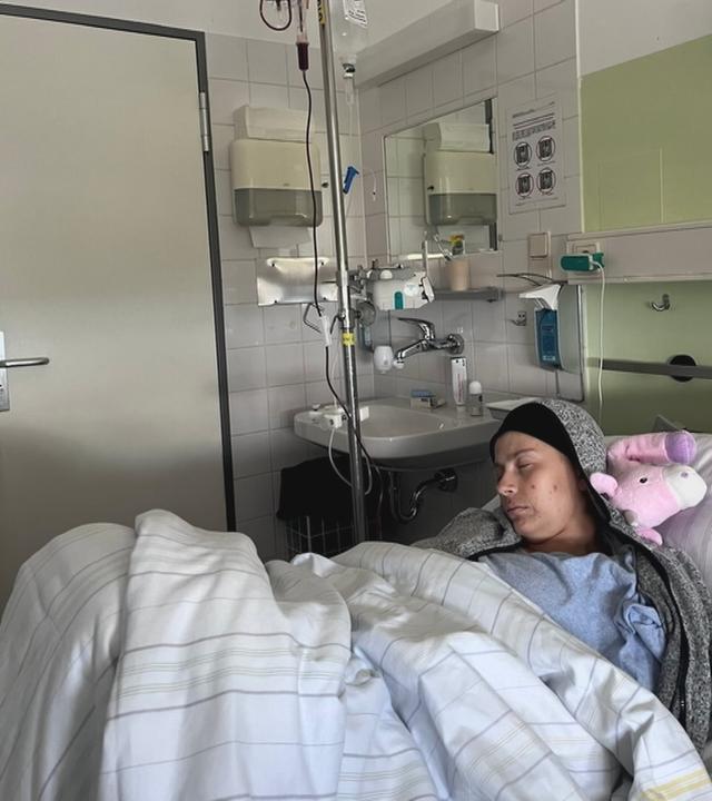 Junge Frau liegt schwer krank mit Krebs im Bett eines Krankenhauses