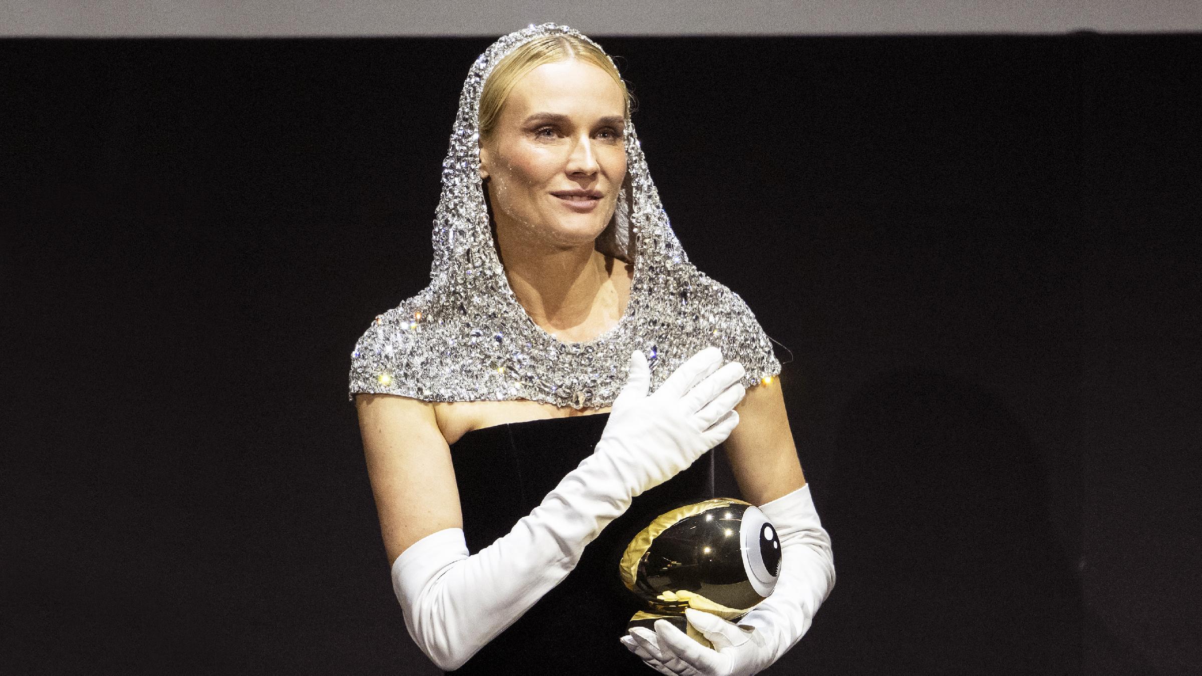 Diane Kruger steht auf einer Bühne und hält einen Golden Eye Award.