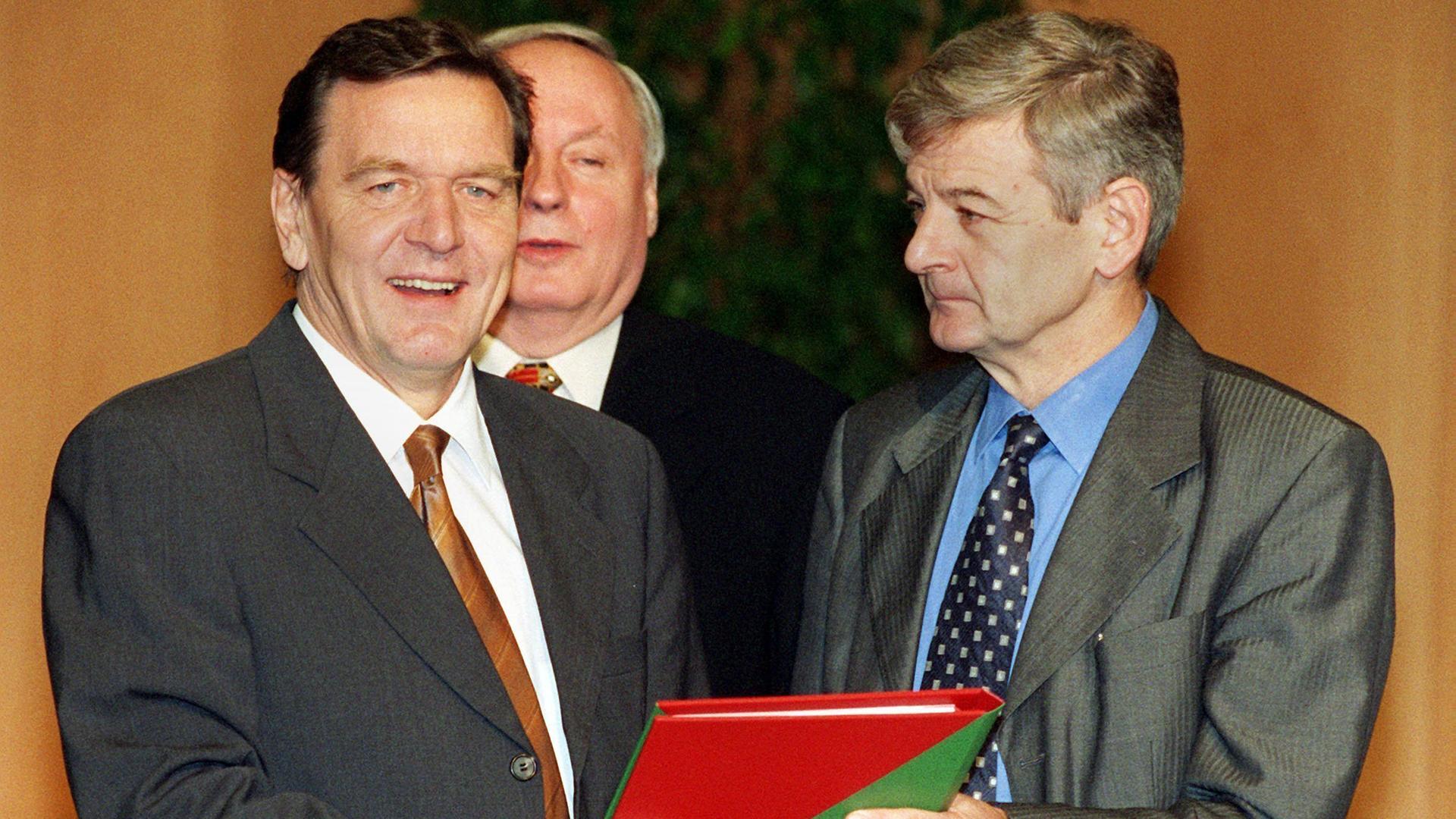 "Die 90er - Jahrzehnt der Chancen: 1997-1999: Bimbeskanzler und Arschgeweih": Gerhard Schröder und Joschka Fischer halten den rot-grünen Koalitionsvertrag. Oskar Lafontaine steht im Hintergrund, 1998.