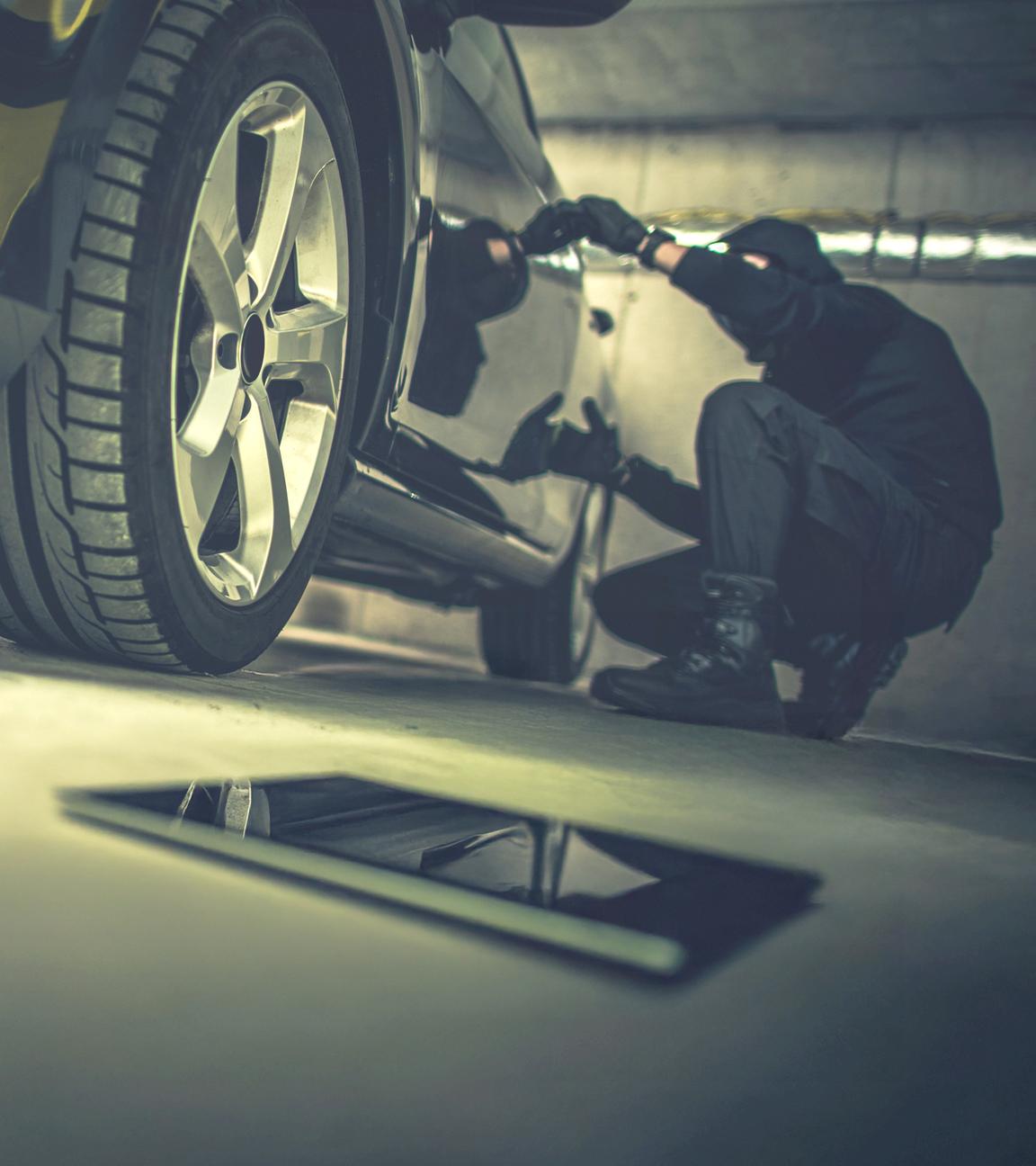 Autoknacker bei der Arbeit in einer Tiefgarage, im Vordergrund liegt ein Tablet
